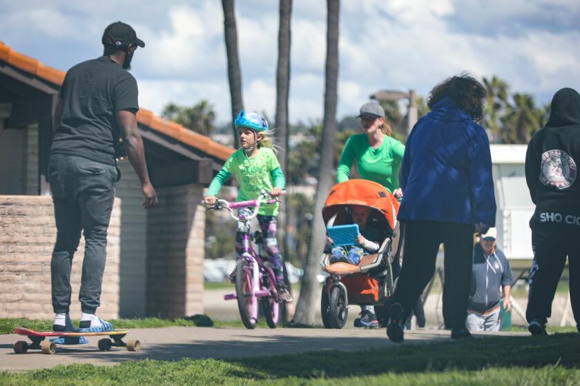 With the schools and many businesses closed due to the coronavirus outbreak, many people headed to Mission Bay Park. Here, they walked and rode along the path at Leisure Lagoon, March 17, 2020 in San Diego, California.