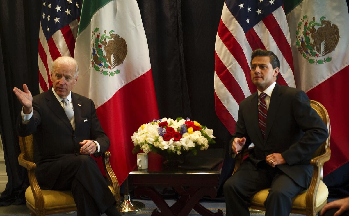 Joe Biden sits with Enrique Peña Nieto in front of U.S. and Mexican flags