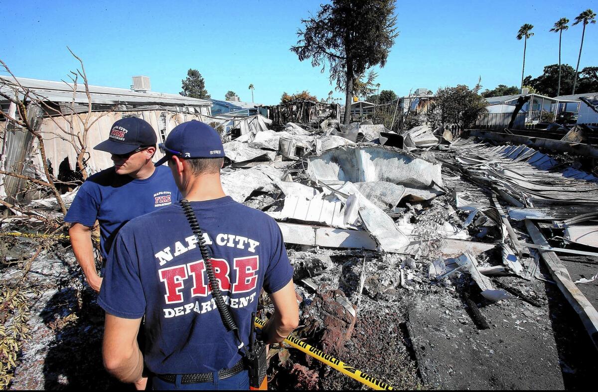 Emergency workers stand amid the remains of a mobile home destroyed by a fire after the 6.0 earthquake in Napa.