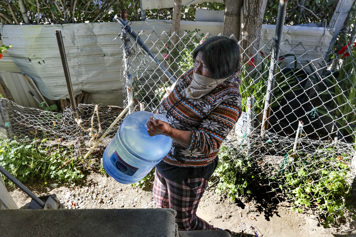 Esperanza Sanchez carries drinking water delivered by a Coachella Valley Water District truck.