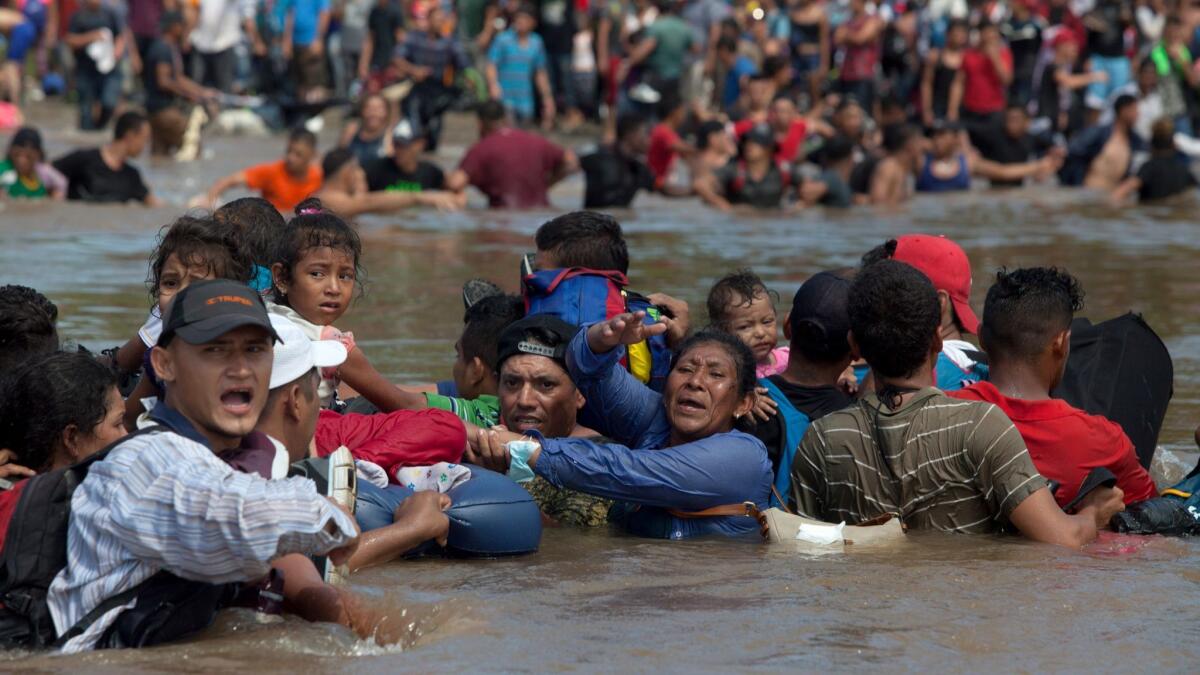 Honduran migrants shout for others to join them as migrants form a human chain to cross the Suchiate River, which separates Mexico and Guatemala, on Oct. 29, 2018.