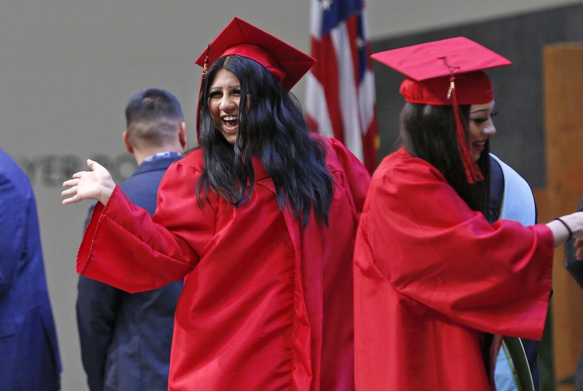 Graduate and student speaker Breanna Fuentes, left, waves to family and friends as she picks up her diploma on Thursday.