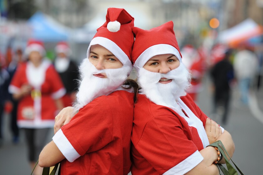 two people dressed as Santa Claus standing back to back