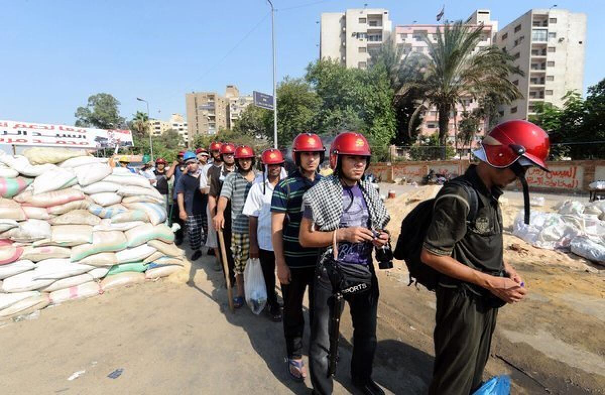 Egyptian supporters of deposed President Mohamed Morsi wear helmets and carry sticks during a march against the government.