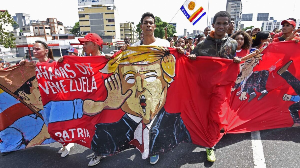 Supporters of Venezuelan President Nicolas Maduro hold a banner mocking President Trump during a pro-government march on May 1, 2019, in Caracas.