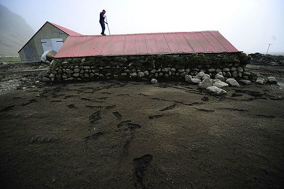 A farmer in Steinar, Iceland, cleans the roof of a goat house dirtied by heavy ash from the active Eyjafjallajokull volcano.