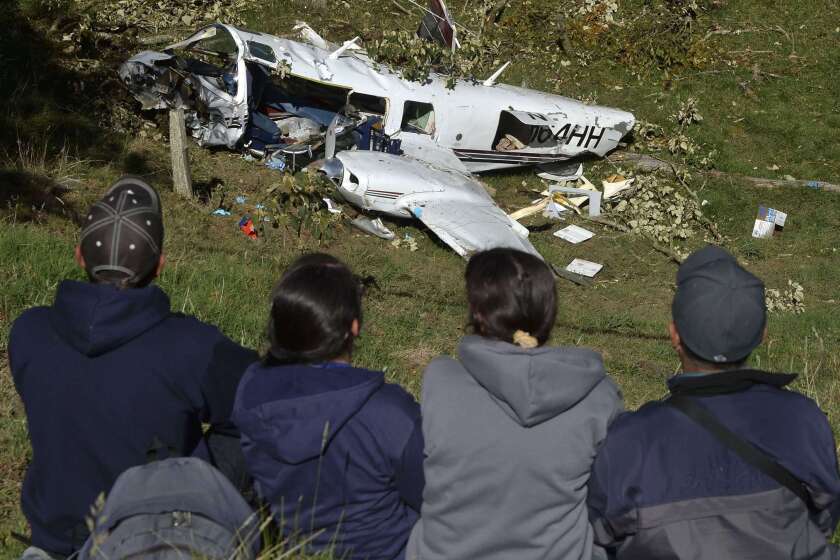 People look at the wreckage of a Piper PA-60 Aerostar twin-engine aircraft that crashed near San Pedro de los Milagros, east of Medellin, Colombia. The plane's three occupants were making a movie starring Tom Cruise. Two died.