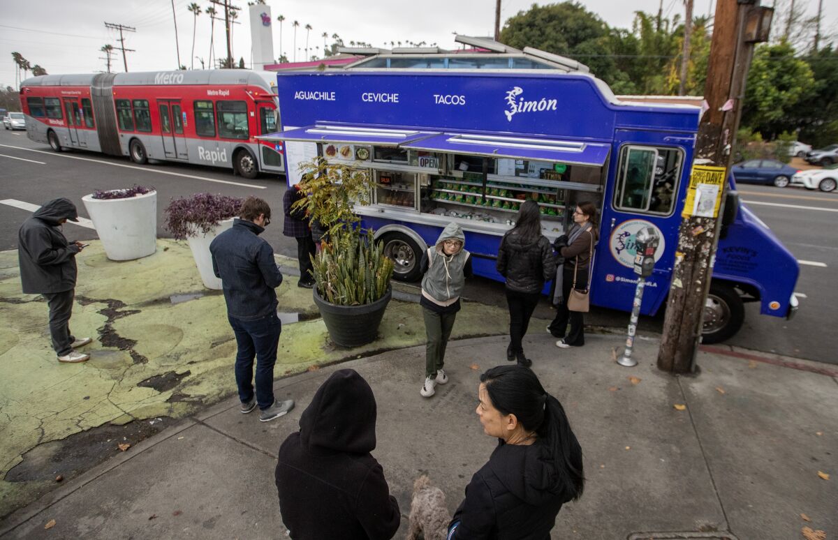 Customers wait for their orders at the Simón mariscos truck parked at the Sunset Triangle Plaza.