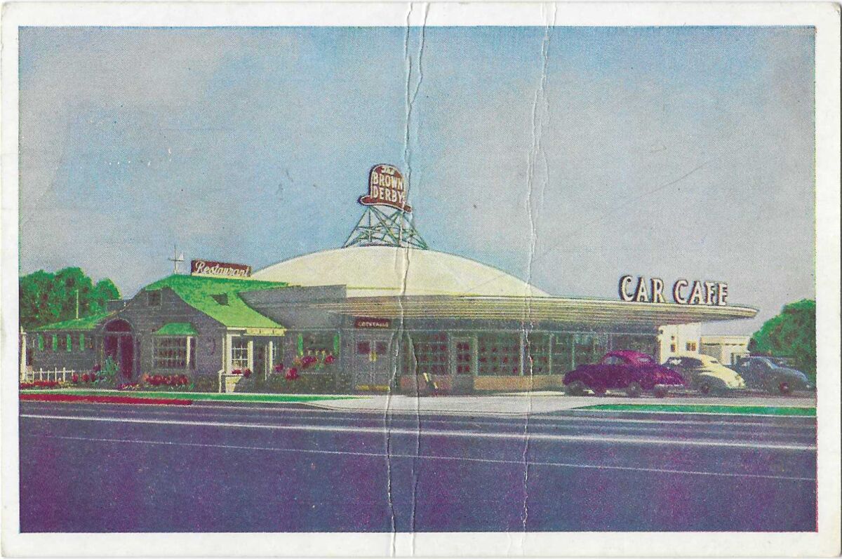 A vintage postcard shows the Brown Derby Car Cafe, with a red, a white and a blue car in the lot.