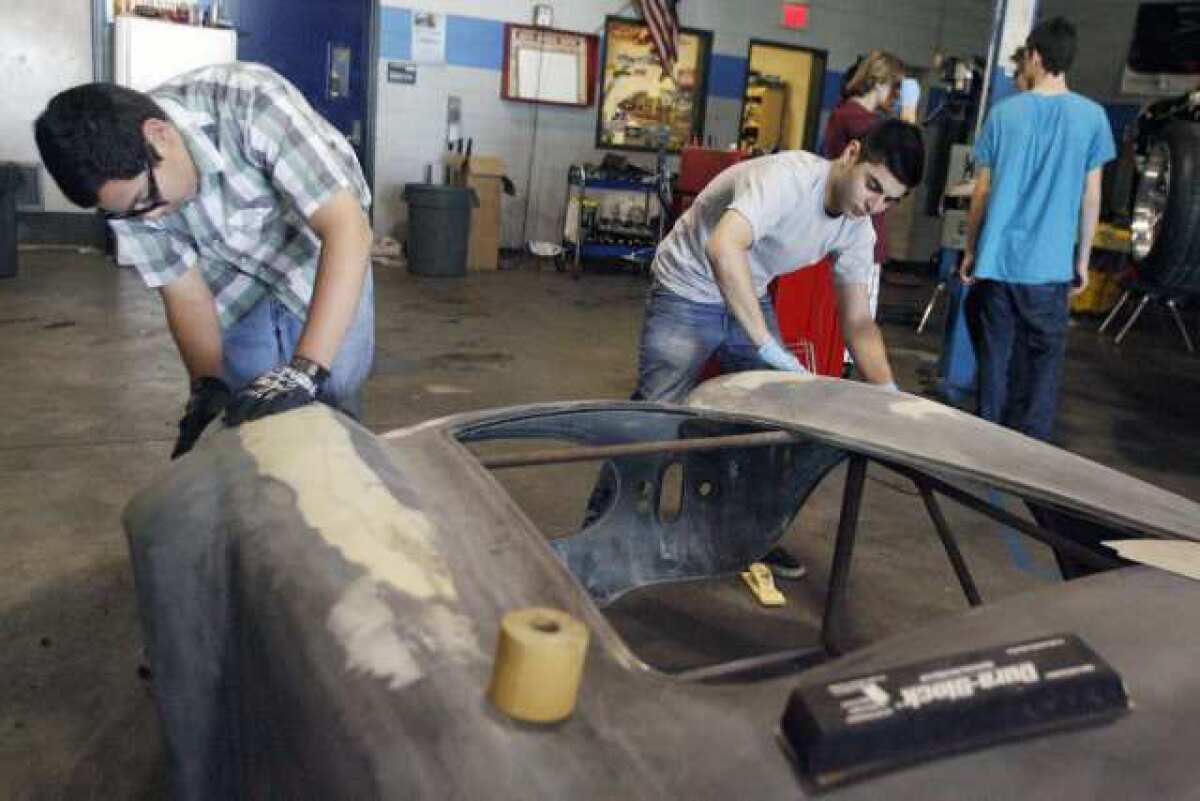 Alonso Sicairos, 16, left, and Dan Mansour, 16, work on the body frame of a Cobra Shelby at Burbank High School on Tuesday. Burbank High School students from the auto shop program will hold their first classic car show fundraiser this Saturday.