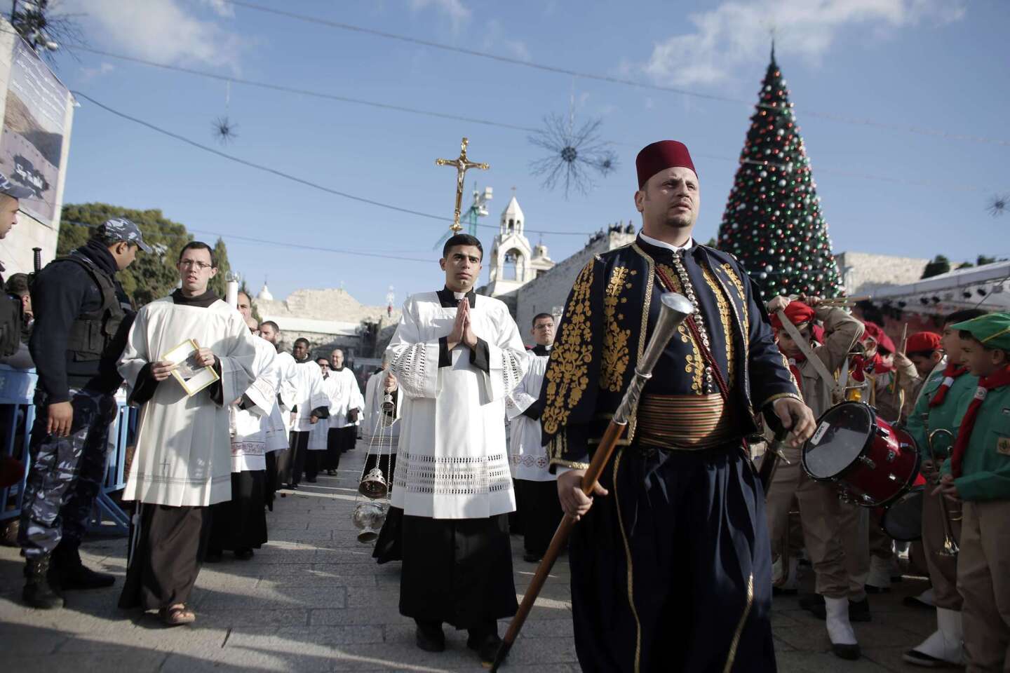 A clergyman holds a crucifix in Manger Square outside the Church of the Nativity as Christians gather for Christmas celebrations in the West Bank city of Bethlehem.