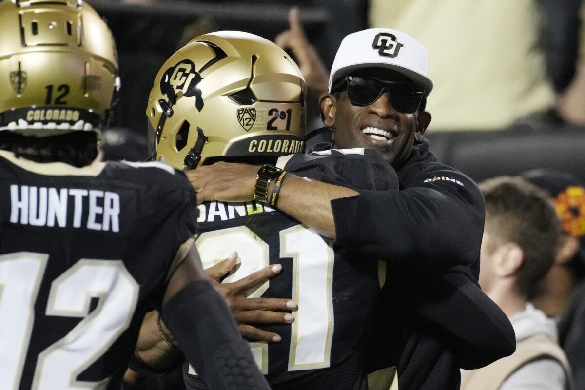 Coach Deion Sanders hugs a player