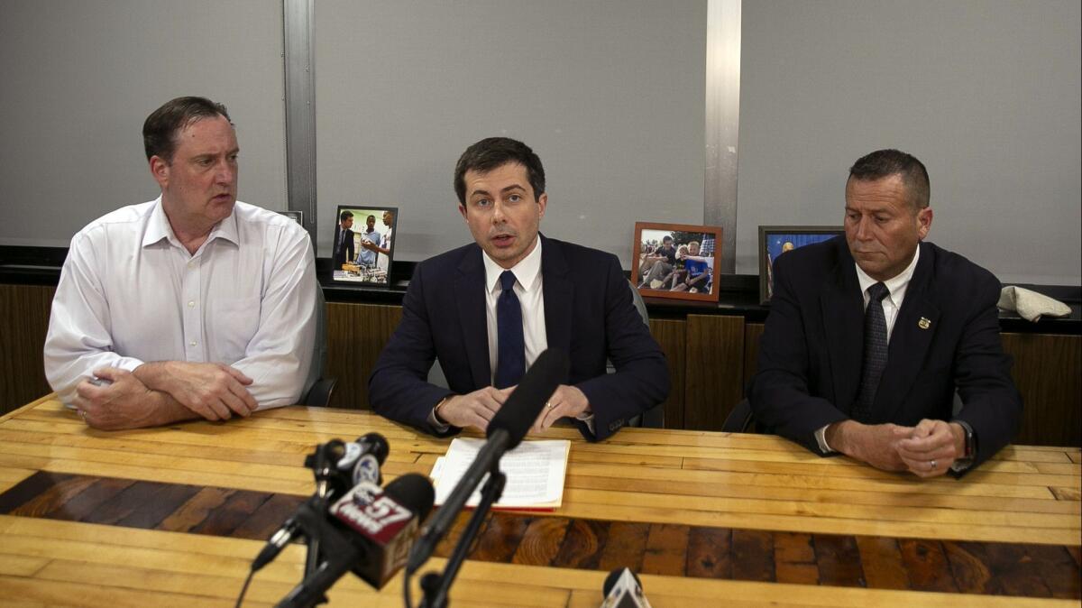South Bend, Ind., Mayor Pete Buttigieg, center, speaks during a news conference, flanked by the common council president and police chief.