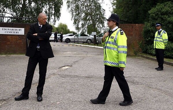 Security guards stand at the gates of Edgwarebury Cemetery in London.