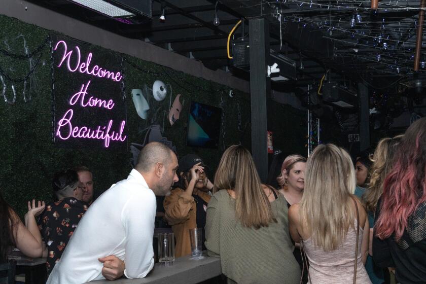 SAN DIEGO, CA - NOVEMBER 04, 2023- Patrons of the lesbian bar, Gossip Grill, in San Diego, CA, enjoy outside seating where just two weeks ago, an arson damaged their patio. Above a sign reads "Welcome Home Beautiful" signifying it a safe space for the local LGBTQ community in San Diego. (Jireh Deng/Los Angeles Times)