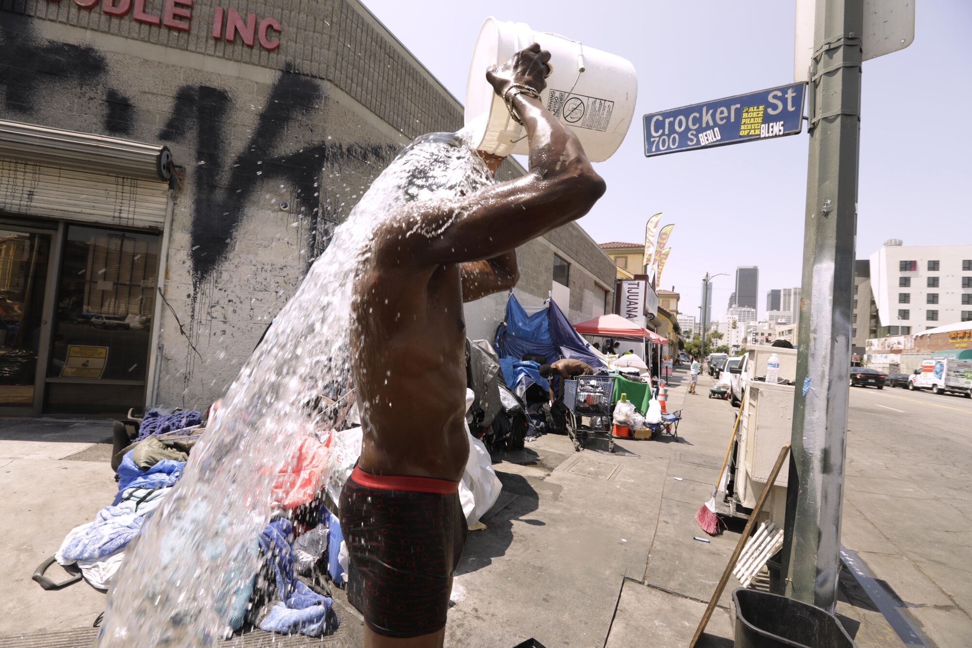 Aug. 12: Dennis Johnson washes himself with a bucket of water on a sidewalk