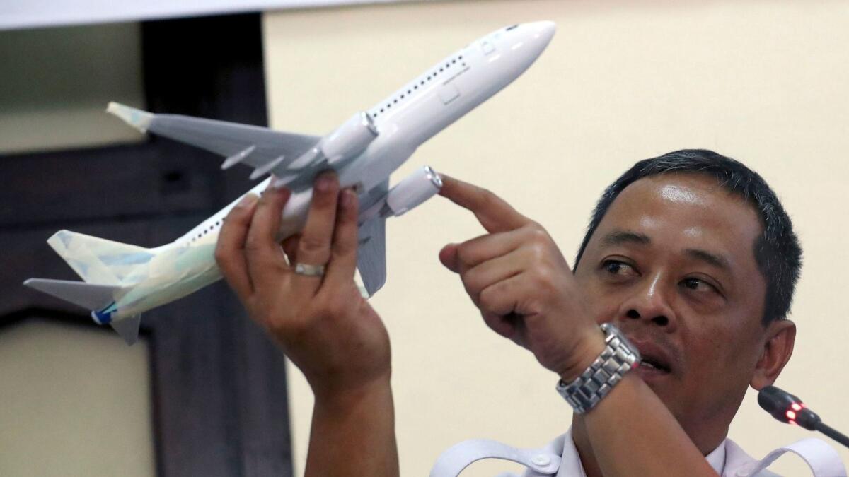 Indonesian National Transportation Safety Committee investigator Nurcahyo Utomo holds a Boeing 737 aircraft model as he answers questions from journalists.
