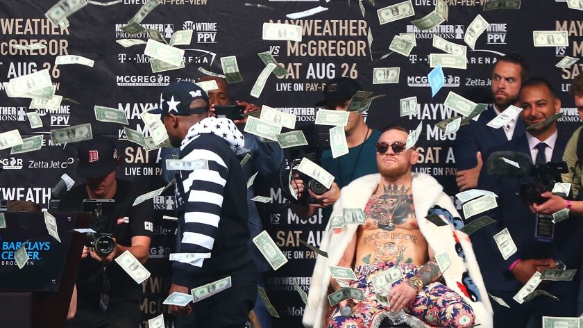 Money rains down on Floyd Mayweather Jr., front left, and Conor McGregor during a press event at Barclays Center in Brooklyn on July 13.