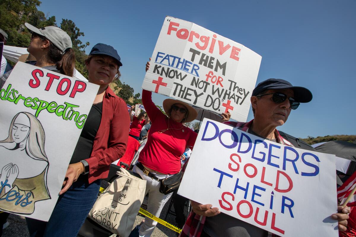 Protesters hold signs as they gather outside Dodger Stadium ahead of Pride Night.