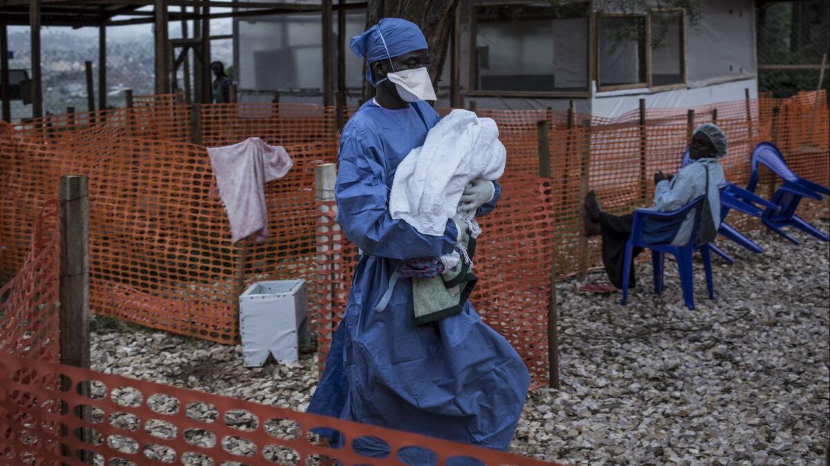 A caretaker already cured of Ebola carries a 4-day-old baby suspected of having the deadly hemorrhagic fever into a treatment center in Butembo, Congo.