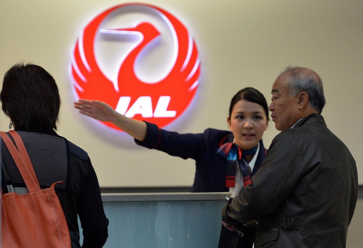 A Japan Airlines employee directs a passenger at Tokyo's Haneda airport in October.