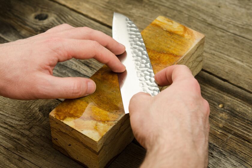 A person uses a whetstone to sharpen a knife.