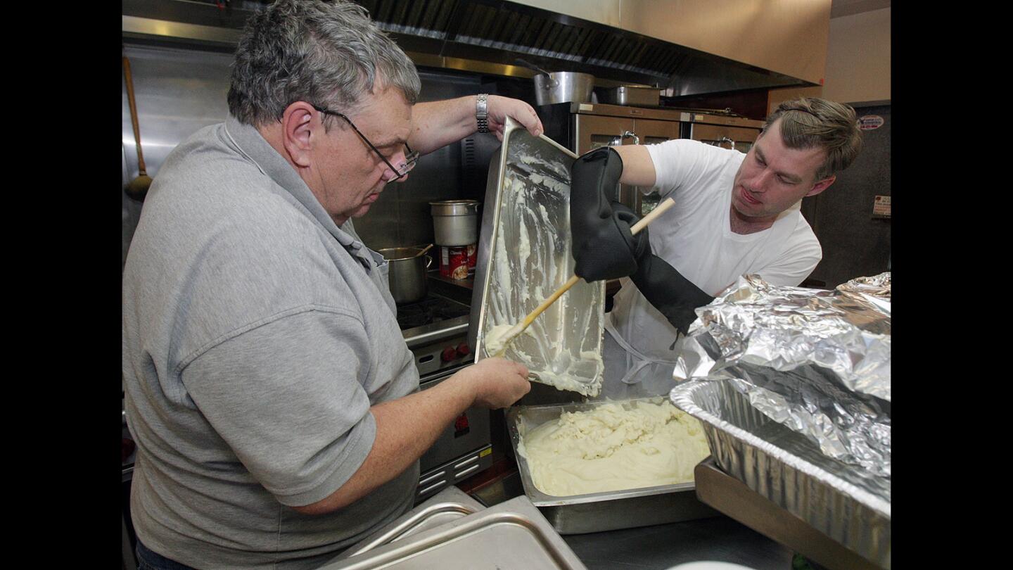 Thanksgiving cook Lloyd Ferguson and Jon Hernon, of Los Angeles, pour mashed potatoes into a serving pan at the Salvation Army Glendale Corps and Community Center Thanksgiving dinner in Glendale on Thursday, Nov. 26, 2015.