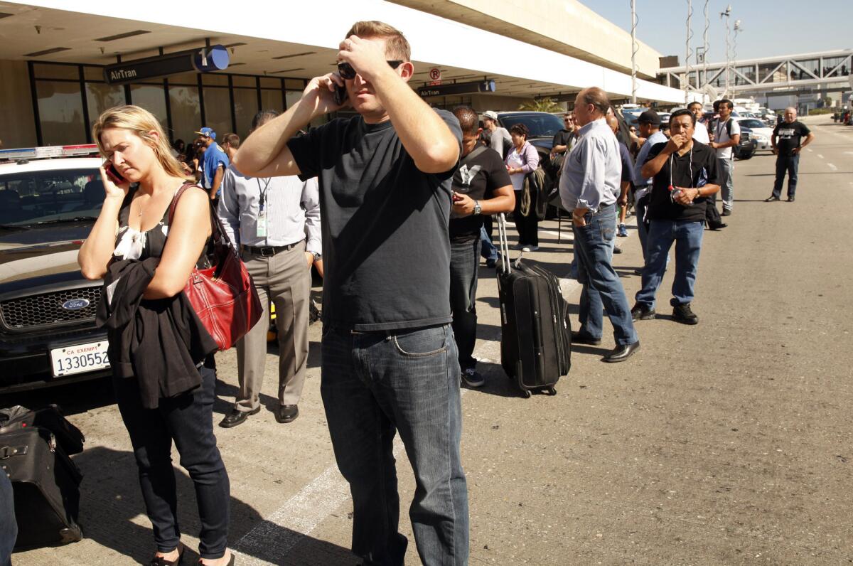 Travelers line the roadway of LAX after they were evacuated when a day a gunman hunted Transportation Security Administration officials in Terminal 3.