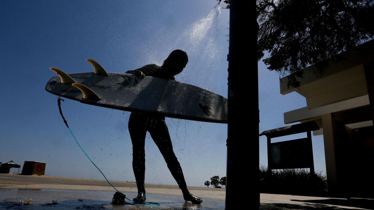 Petri Carson rinses off the sand and salt water after a day of surfing at Doheny State Beach.
