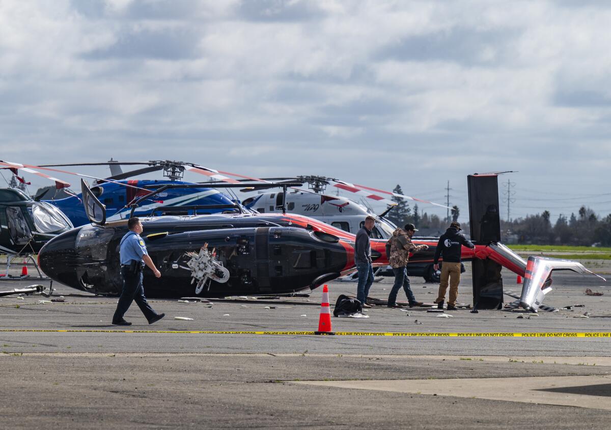 Officials inspect a crashed helicopter lying on its side at Sacramento Executive Airport. 