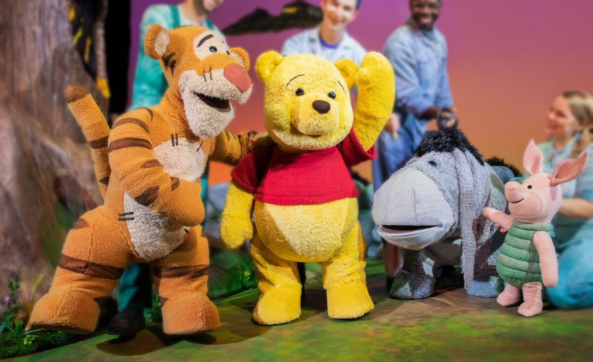 Tigger, Winnie the Pooh, Eeyore and Piglet puppets stand next to one another.