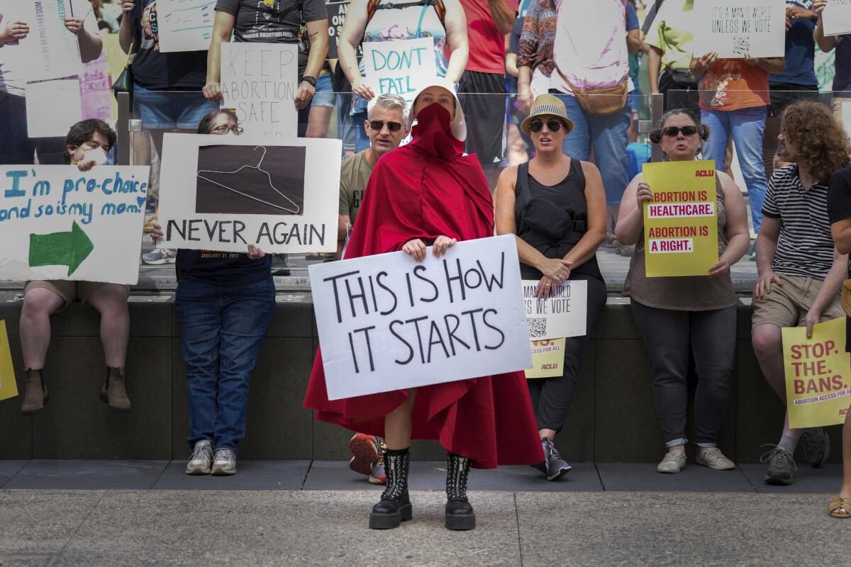 Abortion-rights protesters include a person in a "Handmaid's Tale" costume with a sign reading "This Is How It Starts."