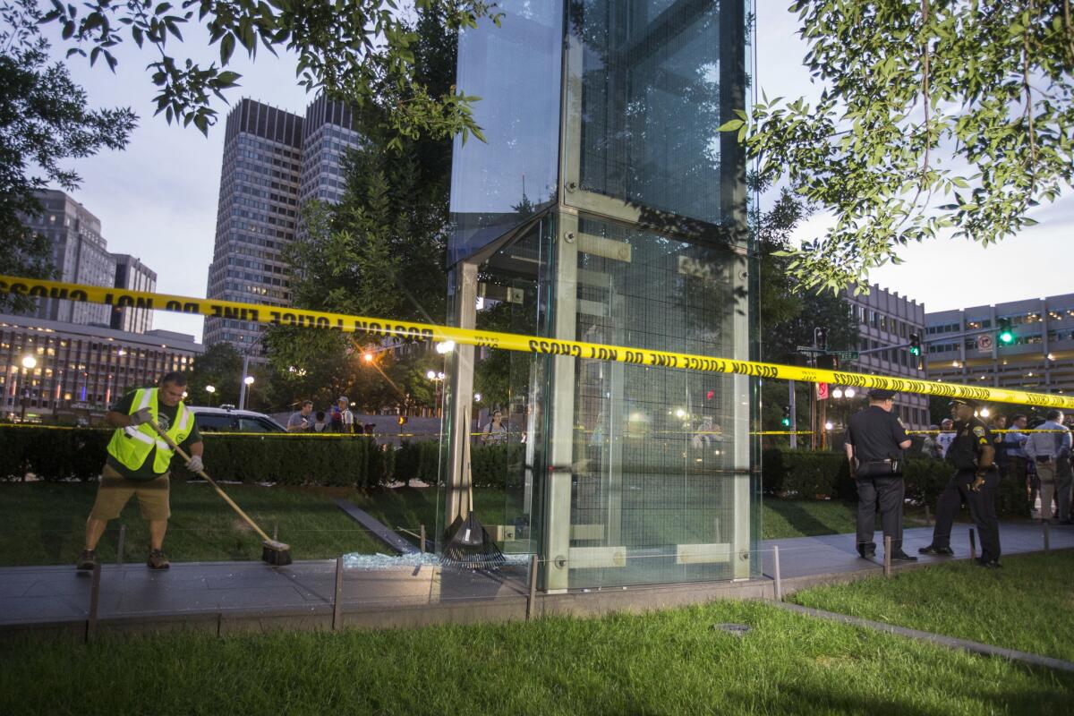 A worker cleans up broken glass at the New England Holocaust Memorial after police said a rock was thrown through a glass panel on the memorial in Boston on Aug. 14.