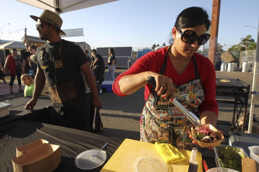 Claudia Toscano makes a taco as she and her cousin Cesar Toscano operate their food business called Coal Bros during the City Heights Street Food Festival on Thursday , September 12, 2019 in San Diego, California.