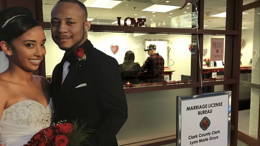 A cardboard cutout of a happy bride and groom advertises the Vegas airport's temporary marriage license bureau as Blake Seddens and Mandy Georgeson of Clovis, Calif., get their license inside.