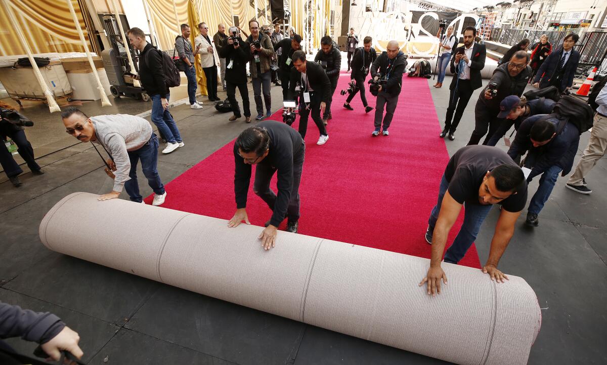 Pascual Rosas, left, Rudy Morales and Pablo Cruz roll out the red carpet on Hollywood Boulevard in preparation for the Oscars.