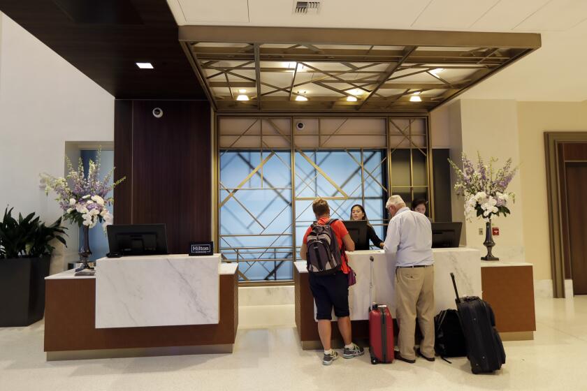 FILE- In this Sept. 5, 2018, file photo guests stand at the front desk at the Embassy Suites by Hilton hotel in Seattle's Pioneer Square neighborhood in Seattle. (AP Photo/Ted S. Warren, File)