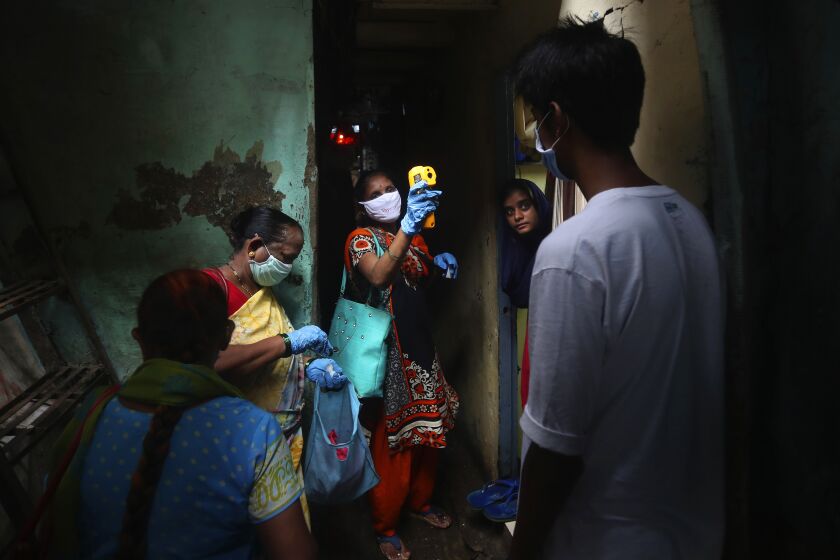 FILE - In this Monday, July 6, 2020, file photo, a health worker screens people for COVID-19 symptoms at Dharavi, one of Asia's biggest slums, in Mumbai, India. The worldwide death toll from the coronavirus eclipsed 1 million, nine months into a crisis that has devastated the global economy, tested world leaders' resolve, pitted science against politics and forced multitudes to change the way they live, learn and work. (AP Photo/Rafiq Maqbool, File)