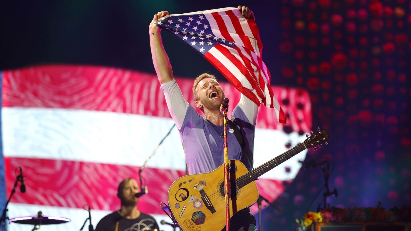 Chris Martin of Coldplay holds up an American flag as the band performs at SDCCU Stadium on Oct. 8, 2017. (Photo by K.C. Alfred/The San Diego Union-Tribune)