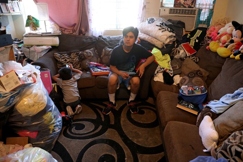 LOS ANGELES, CA - JUNE 15: Jesse Davila, 19, right, shown with his younger brother Lino Galicia, 3, takes a break before going to his construction job, in the family's one-bedroom apartment in the Pico-Union neighborhood on Wednesday, June 15, 2022 in Los Angeles, CA. There are eight family members sharing a one bedroom unit. Magdalena Garcia, 40, and husband Edgar Galicia, 48, live with their six children in a one-bedroom apartment. Magdalena has lived in the unit over 20 years. Overcrowded housing in Pico-Union, considered the most overcrowded neighborhood in Los Angeles. (Gary Coronado / Los Angeles Times)