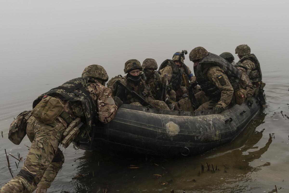 Ukrainian marines in a dinghy pushing off from the bank of the Dnipro River