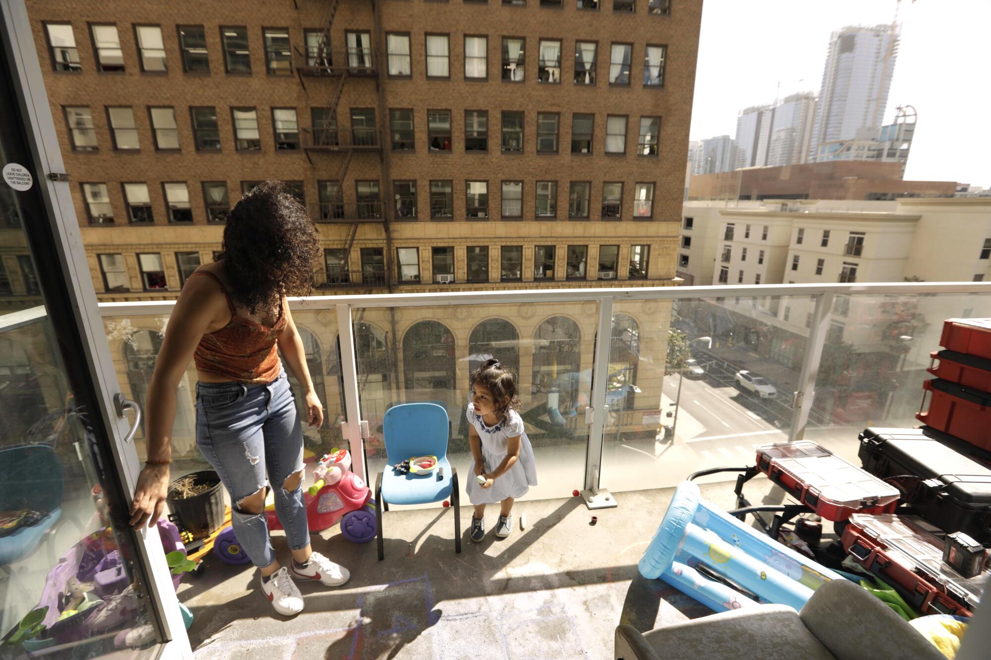 A woman watches a little girl play on a balcony