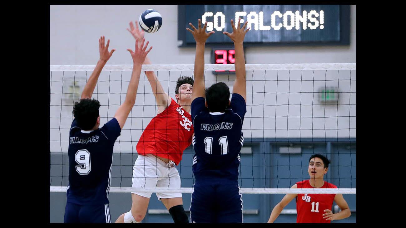 Burroughs High School boys volleyball player #32 Cole Katz spikes the ball in front of #9 Garo Barsemian and #11 Ricky Phagoo in away game vs. La Crescenta High School, in La Crescenta on Friday, April 6, 2018.