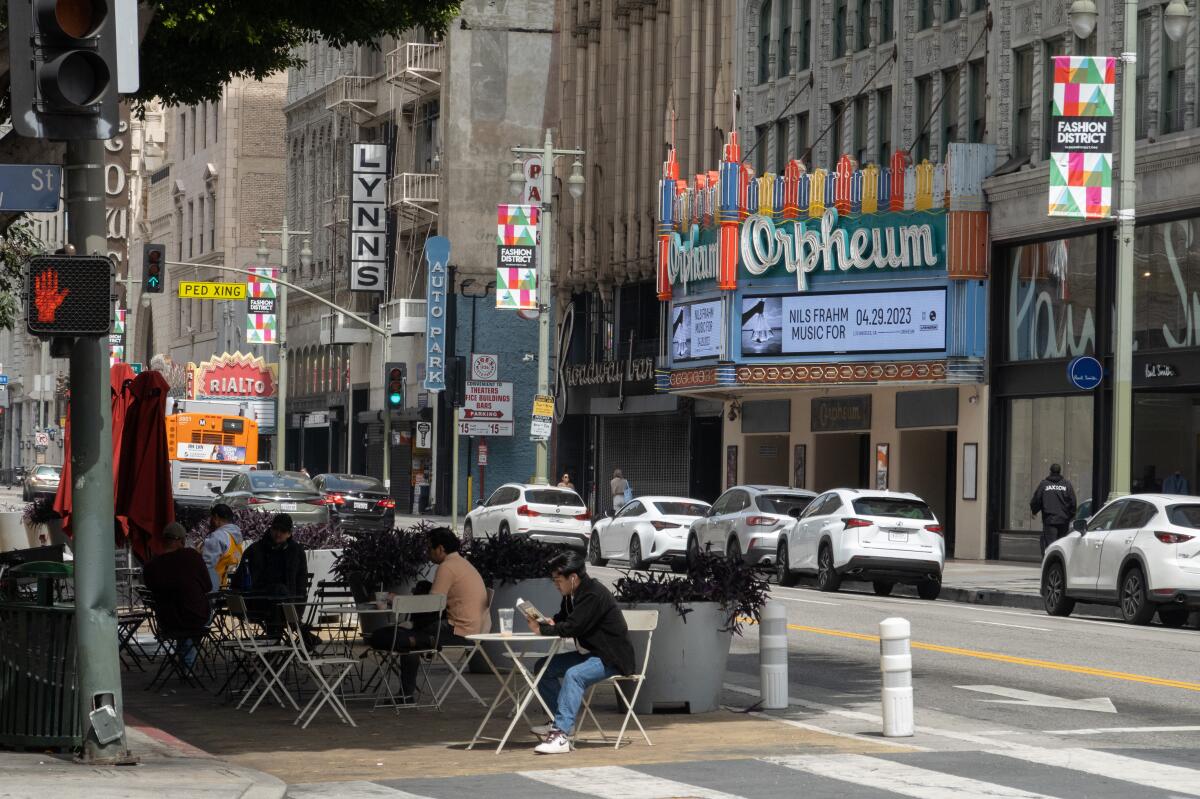 People seated at a patio across the street from the Orpheum Theatre in downtown Los Angeles