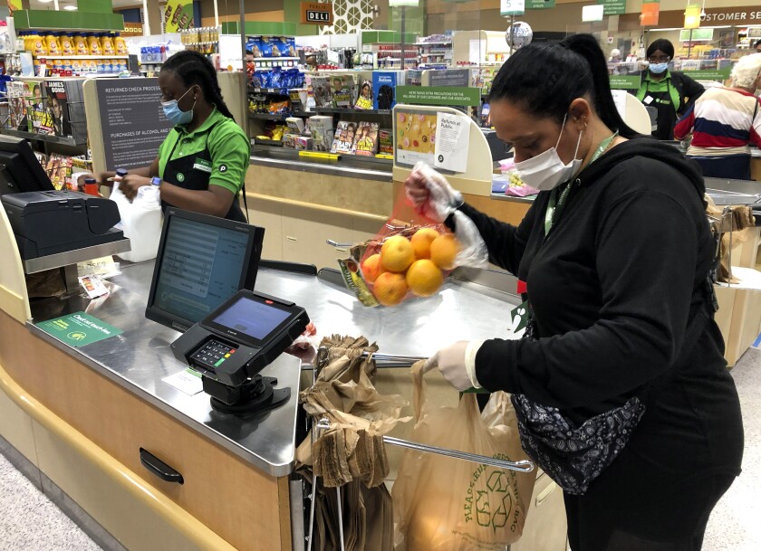 Instacart shopper Yelitza Esteva, right, bags groceries for an order at a grocery store in Surfside, Fla., in April.