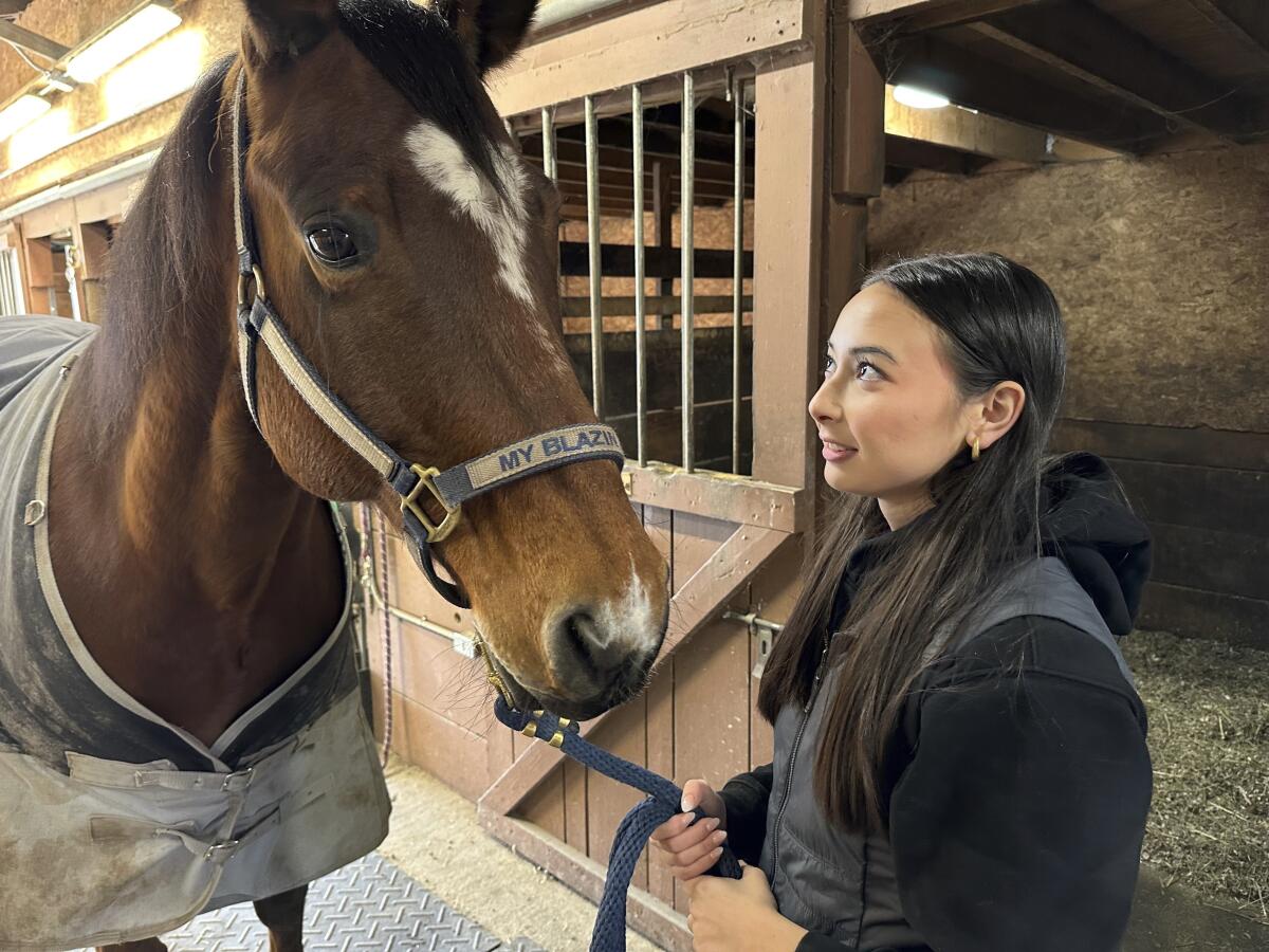 Kylie Ossege looks at her horse, Blaze, at a boarding facility.