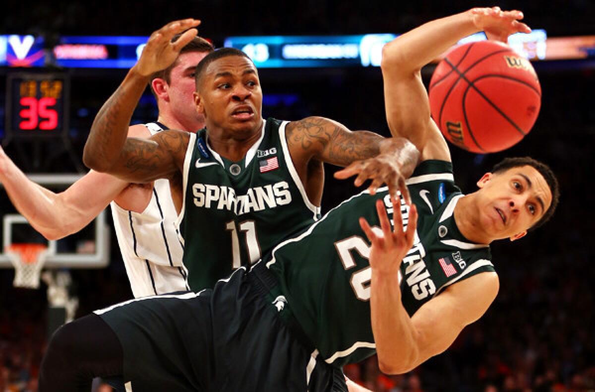 Michigan State teammates Keith Appling (11) and Travis Trice (20) try to secure a loose ball in their victory over Virginia on Friday night in an East Regional semifinal in New York.