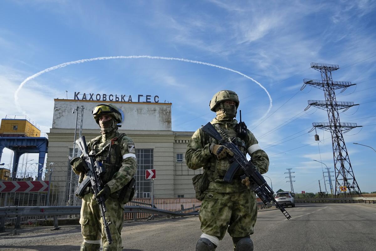 FILE - Russian troops guard an entrance of the Kakhovka Hydroelectric Station, a run-of-the-river power plant on the Dnieper River in Kherson region, southern Ukraine, May 20, 2022. The Kherson region has been under control of the Russian forces since the early days of the Russian military action in Ukraine. Russia and Ukraine have trade blame over shelling of the Zaporizhzhia nuclear power plant, Europe's largest.This photo was taken during a trip organized by the Russian Ministry of Defense. (AP Photo, File)