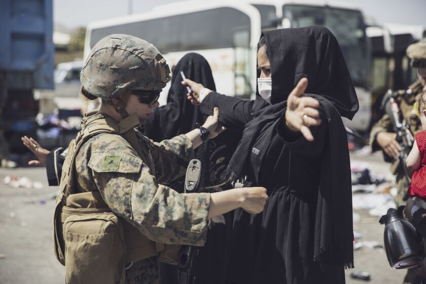 A U.S. Marine checks an Afghan woman as she goes through the evacuation control center at Kabul's airport on Saturday.
