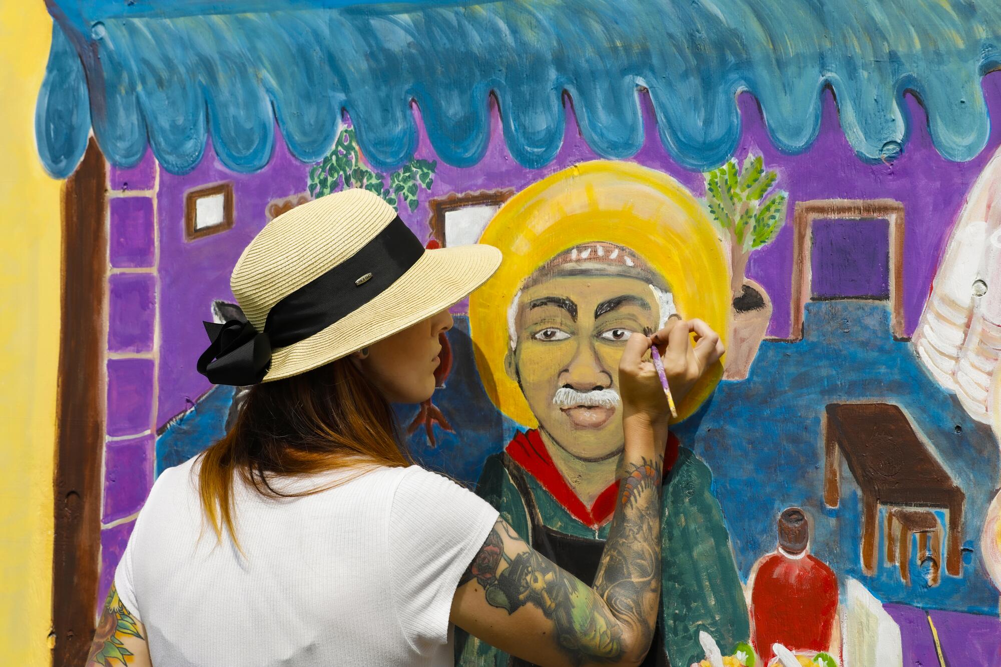 Shirish Villasenor paints the detail work on one of the mural wall panels in Lincoln Park. 